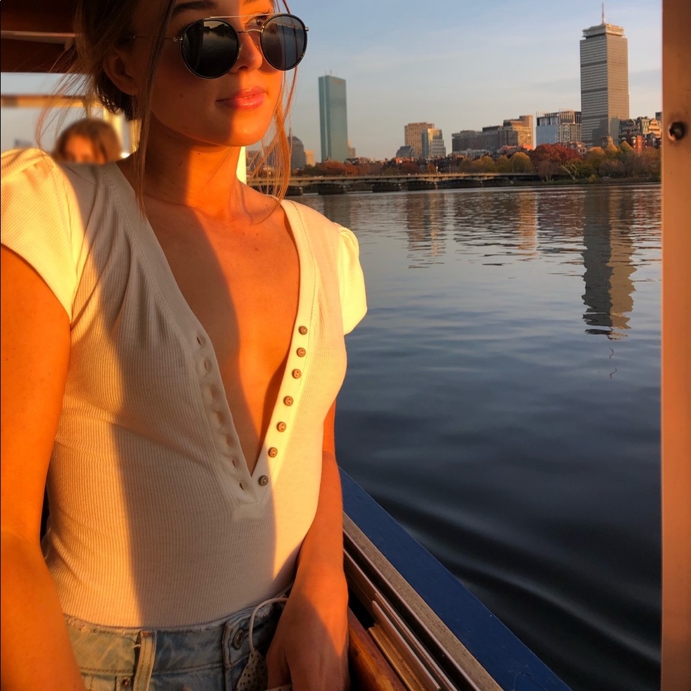 White ribbed bodysuit with a plunging neckline and detailed shoulders